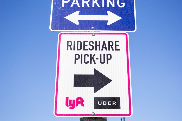 A view of a street sign guiding drivers and riders to the Lyft and Uber loading area.